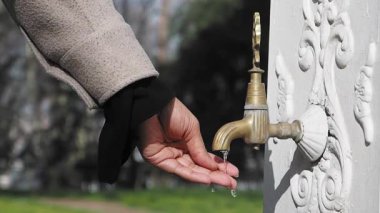Parktaki musluktan su almak için uzanan biri var..