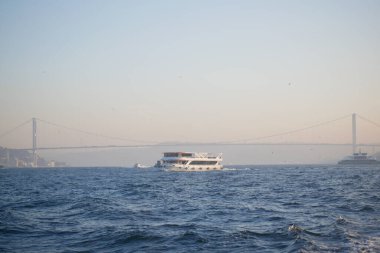 Bir yolcu gemisi alacakaranlıkta bir sahil köprüsünün altında süzülüyor..