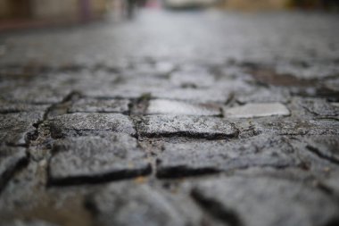 Yağmurdan sırılsıklam olmuş kaldırım taşı sokakları, yağmurdan sonra hafif ışıkta parlıyor..