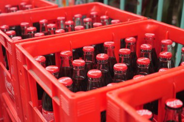 Coca Cola şişeleri bir içecek dağıtım merkezinde kırmızı sandıklarda dizilmiş..