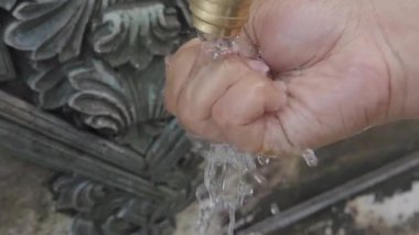 Bir el sıkıca musluğu tutar, içinden su akar..