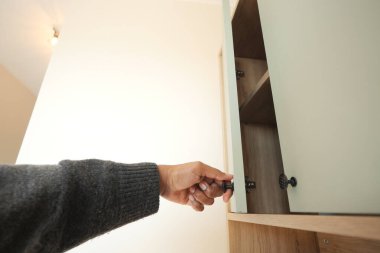 Bir kişi şık bir iç mekanda açık yeşil bir dolap kapısı açıyor..