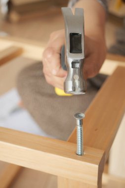 Bir insan evdeki tahta bir yapıya vida çakıyor..