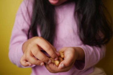 Genç bir kız otururken fındık yiyor. 