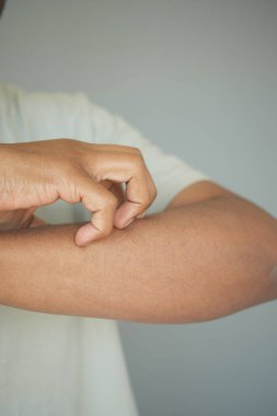 Bir birey nazikçe kolunu kaşır, rahatsızlık belirtileri gösterir..