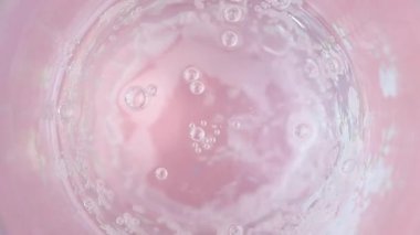 Temiz su kabarcıkları canlı pembe bir zemin üzerinde sergiler.