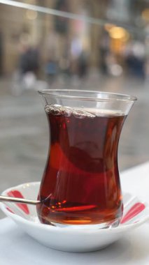 Canlı bir kentsel alanda, masanın üzerinde dumanı tüten bir fincan çay duruyor..