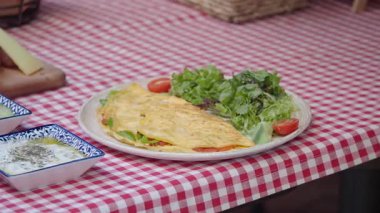 Sıcak bir ortamda canlı bir salata eşliğinde lezzetli bir omletin tadını çıkarın..
