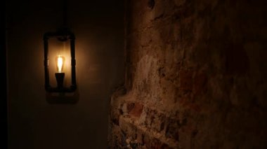 Eski moda aydınlatma armatüründen hafif bir parıltı, desenli tuğla bir duvarı aydınlatır..