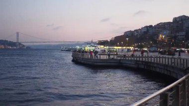 İstanbul 'da güneş batarken insanlar rıhtım boyunca yürüyorlar.