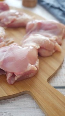 Mutfakta ahşap bir kesme tahtasının üzerinde taze tavuk butları dilimlemek..