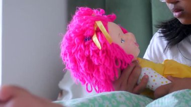 Bir çocuk yatakta renkli bir bebekle oynuyor..