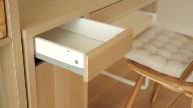 Bir kişi şık bir sandalyede otururken eşyaları çekmeceye yerleştirir..