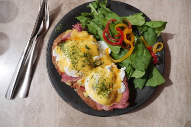 Kahvaltıda jambonlu Benedict yumurta ve canlı salata var..