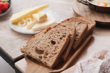 Tahta bir tahtanın üzerinde, yanında peynirle tam tahıllı ekmek dilimleri duruyor..