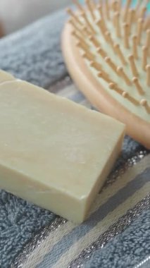 Yumuşak bir havlunun üzerindeki ahşap bir fırçanın yanında yakın plan doğal sabun..