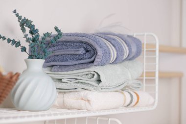 Yumuşak havlular, çiçekli vazonun yanındaki rafta düzgünce düzenlenir..