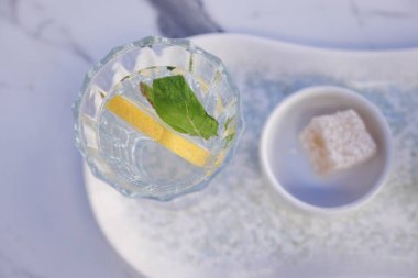 Limon dilimleri ve nane şekeriyle süslenmiş bir bardak limonata..