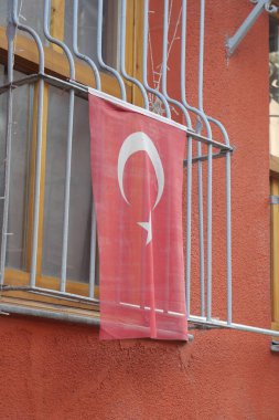 Renkli bir kentsel alanda Türk bayrağı bir balkondan sarkıyor.