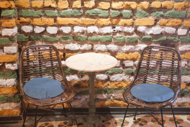 Yastıklı iki şık sandalye renkli bir tuğla duvarın yanında..