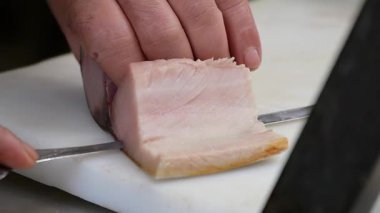 Kesme tahtasında bıçakla balık dilimlemek. .