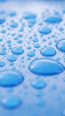 Su damlacıkları pürüzsüz mavi bir yüzey üzerinde karmaşık tasarımlar oluşturur..