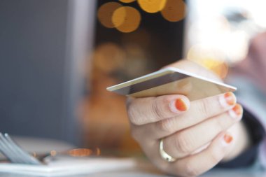 Bir el, hareketli bir kafe masasında otururken kredi kartını tutar..