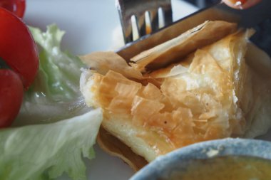 Yumuşak bir Türk Borek taze bir salatanın yanında çatalla kesiliyor..