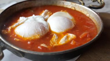 Baharat ve otlarla aromalı domates sosunda haşlanan tuzlu yumurtalar..