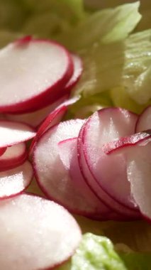 Turplar dikkatlice dilimlenir ve canlı bir yemek için gevrek marulların üzerine yerleştirilir..