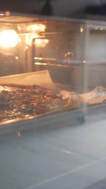 Taze malzemeli pizza fırında pişiyor, mutfağı aromayla dolduruyor..