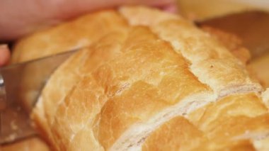 Bir insan sıcak bir somun ekmeği davetkar bir mutfak ortamında dilimliyor..