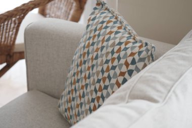 Geometrik desenli şık bir yastık bir kanepede duruyor..