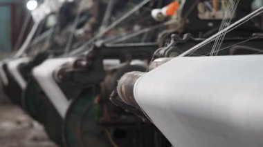 Bir tekstil fabrikasında dönen makinelerle dokuma işlemini gözlemlemek.