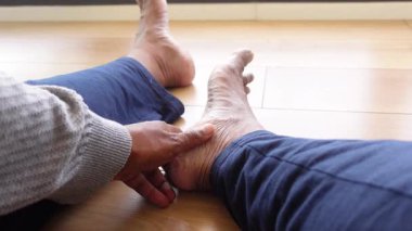 Genç adam ayaklarının acısıyla yerde oturuyor. .