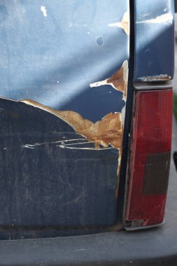 Bir araç, şehir ortamında belirgin boya çizikleri ve pas gösteriyor..