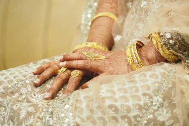 Düğünde kına ve altın aksesuarlarla süslenmiş gelin elleri..