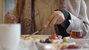 Sıcak bir kahvaltı yerinde insan taze meyve ve çayın tadını çıkarıyor..