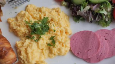 Çırpılmış yumurta ve taze otlar yanında renkli bir salata ve et..