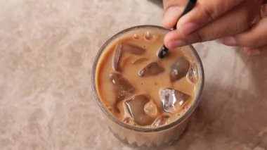 Bir el, buzlu kahveyi karıştırıyor. İçi buz küpleriyle dolu..