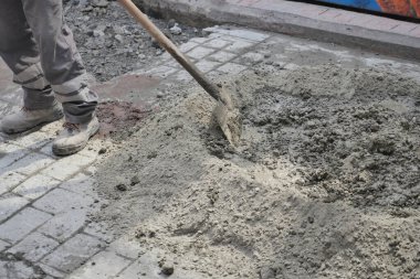 İnşaat işçisi yoğun bir sitede kürek kullanarak betonu karıştırıyor..