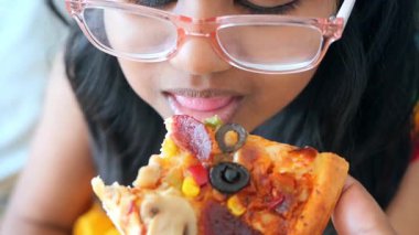 Bir kız zeytin ve sebzeli lezzetli bir dilim pizzayı sever..