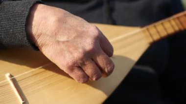 Bir insan dışarıda bir telli çalgı çalar, günün tadını çıkarır..