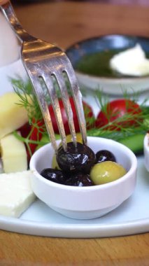 Renkli bir zeytin, peynir, domates ve bitki karışımı sunulur..