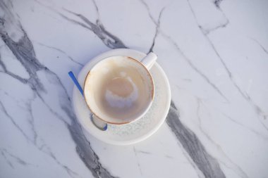 Sıcak bir sabahtan sonra bir kahve fincanı mermer bir masada boş oturur..