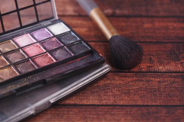 Parlak renkli makyaj paleti yumuşak bir fırçanın yanında duruyor..