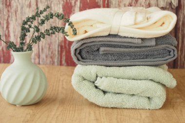 Yeşil vazolu basit bir vazonun yanına yeni katlanmış havlular..