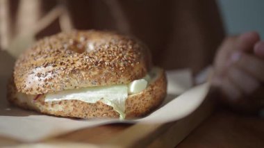 Sıcak bir kafede krem peynir ve taze malzemelerle susamlı simit servis edilir..