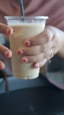 Bir insan rahat bir kafe ortamında dinlenirken buzlu bir kahve yudumlar..