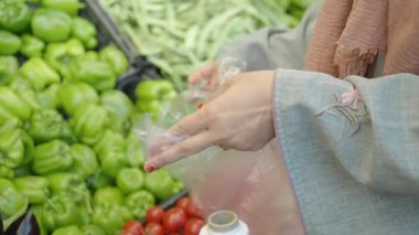 Alışveriş yapan biri markette taze sebze seçer..